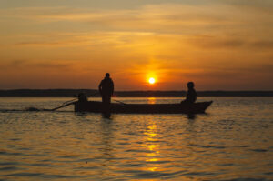 The fishermen and boat silhouette on the lake.