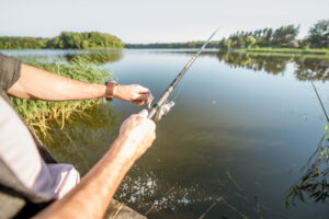 Man reeling in fish at a lake on a warm day