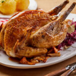 Crispy roasted pheasant with red cabbage , mushrooms, red currants and a sprig of fresh rosemary on an oval platter