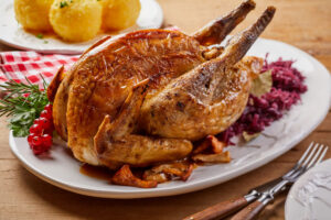 Crispy roasted pheasant with red cabbage , mushrooms, red currants and a sprig of fresh rosemary on an oval platter